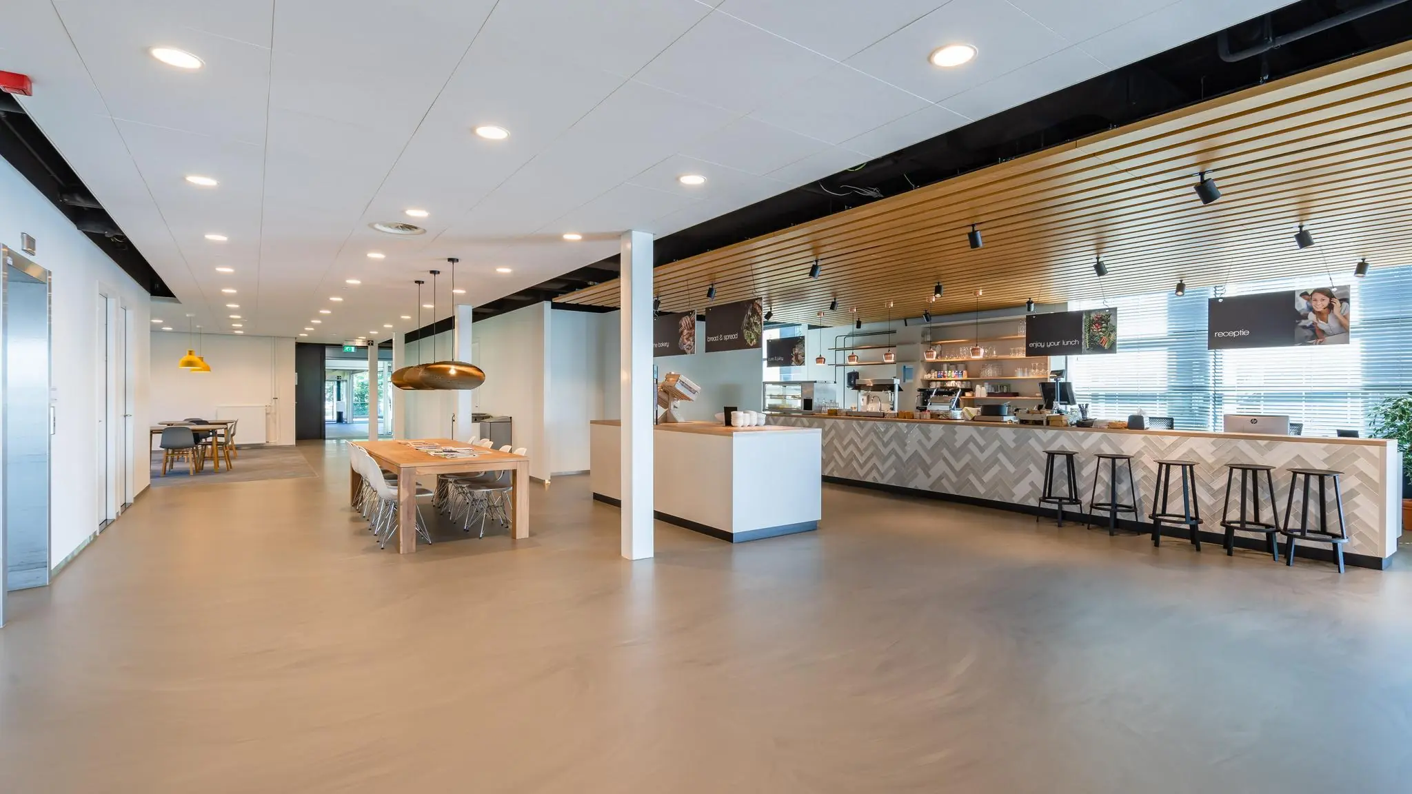 Moderne en ruime bedrijfsrestaurant aan de Rivium Promenade met zithoeken, lange tafels en een koffie- en lunchbar.